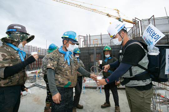 '쌍용 더 플래티넘 광주' 아파트 현장 보건관리자가 '워터보이'로 변신해 현장 곳곳을 다니며 쿨스카프를 착용한 근로자들에게 시원한 물을 제공해 주고 있다.  쌍용건설 제공